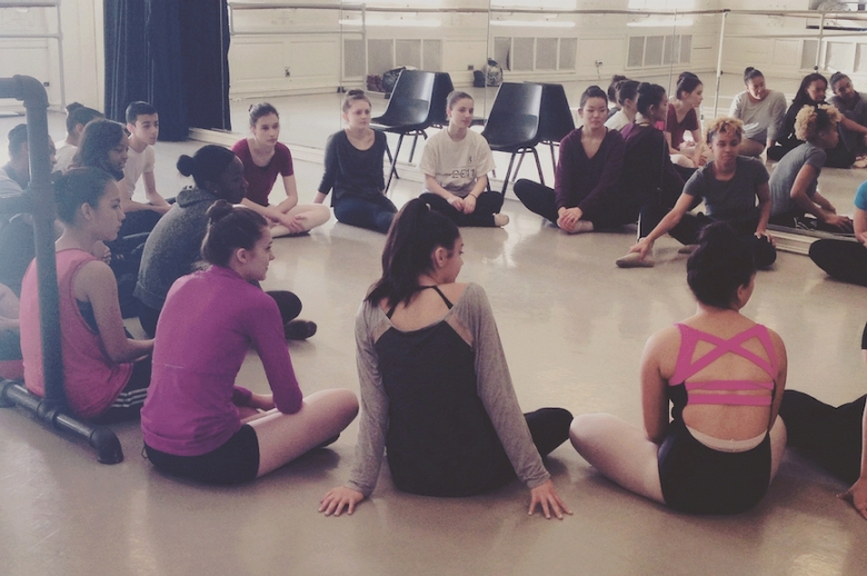 Dancers seated in a circle in studio